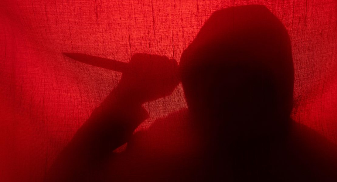 Man with a knife silhouette behind a curtain. Halloween and violence concept; Model Released