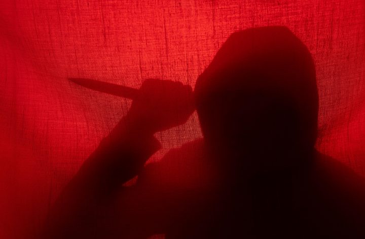 Man with a knife silhouette behind a curtain. Halloween and violence concept; Model Released